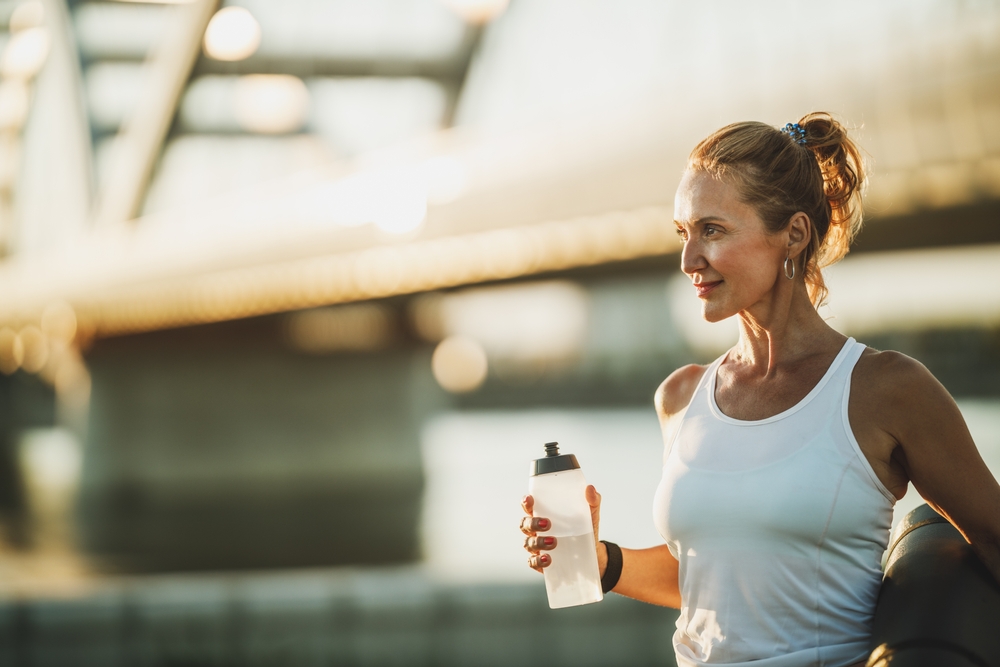 Middle,Age,Sportswoman,Holding,Water,Bottle,Before,Hard,Training,Near