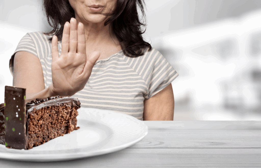 Woman pushing away cake out of fullness.