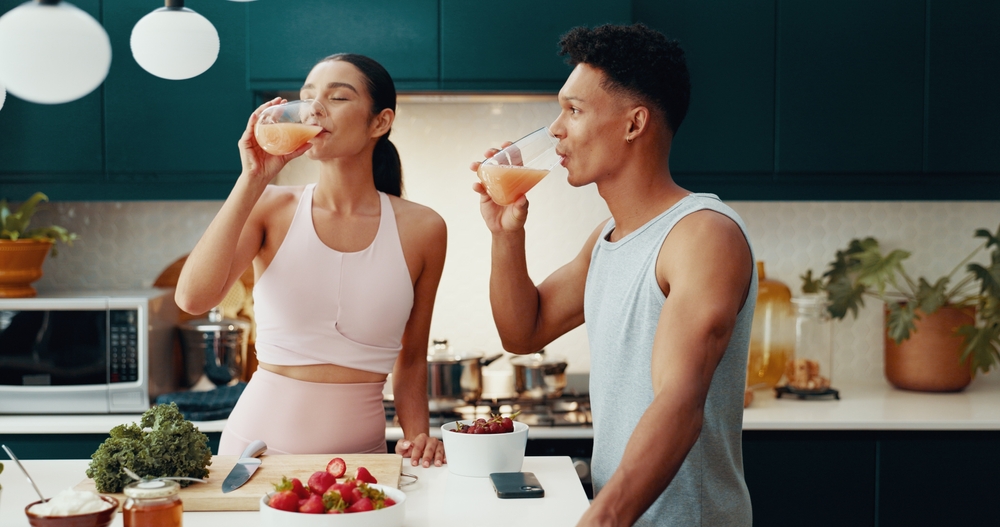 A healthy, active couple drinking nutritious juices in the kitchen, highlighting the vitality goals of KPV peptide therapy at Relive Brentwood.